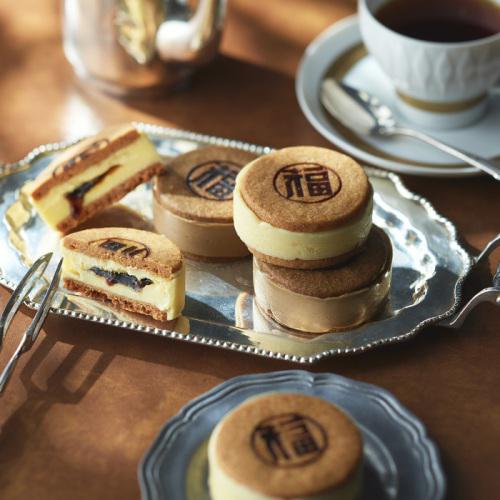 木製のテーブルにのったコーヒーカップやシルバーのオーバル皿の上のバターサンド