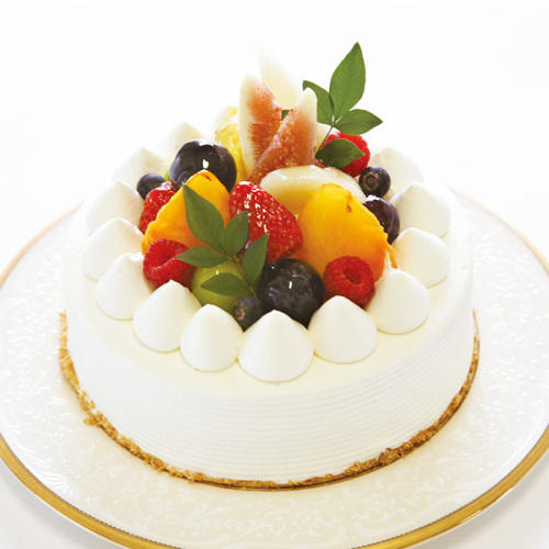 白い皿にのった上にフルーツがたくさん飾られた生クリームのケーキ