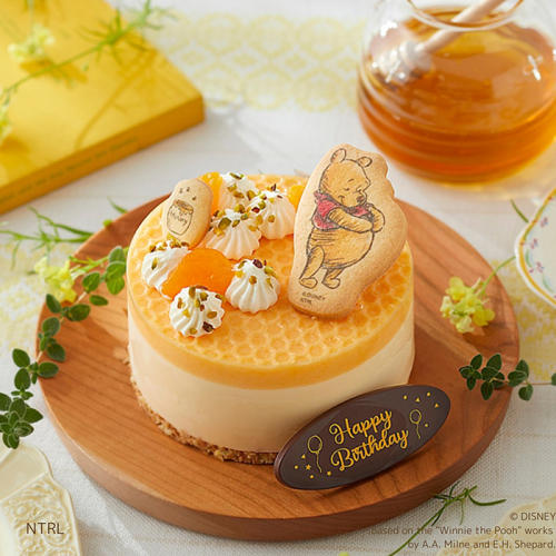 木製の皿にのったケーキリンクの「「トシ・ヨロイヅカ」くまのプーさん／はちみつレモンケーキ」