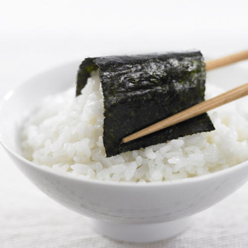 箸を使って海苔でごはんを包み込んでいる様子