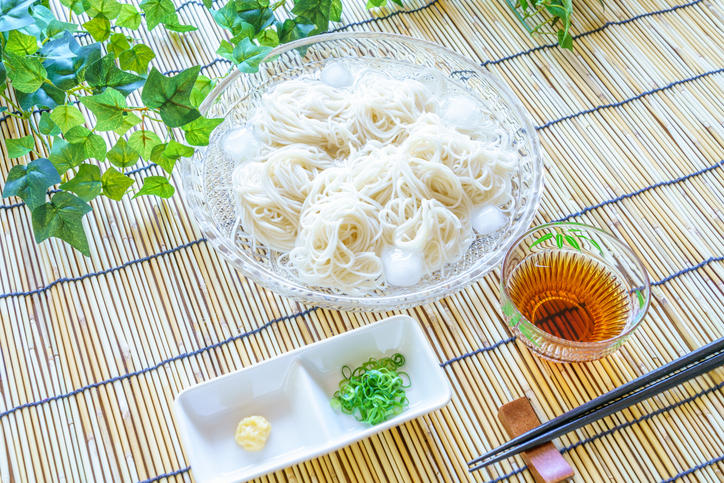 ガラスの器入りのそうめんに薬味とつゆが添えられている様子