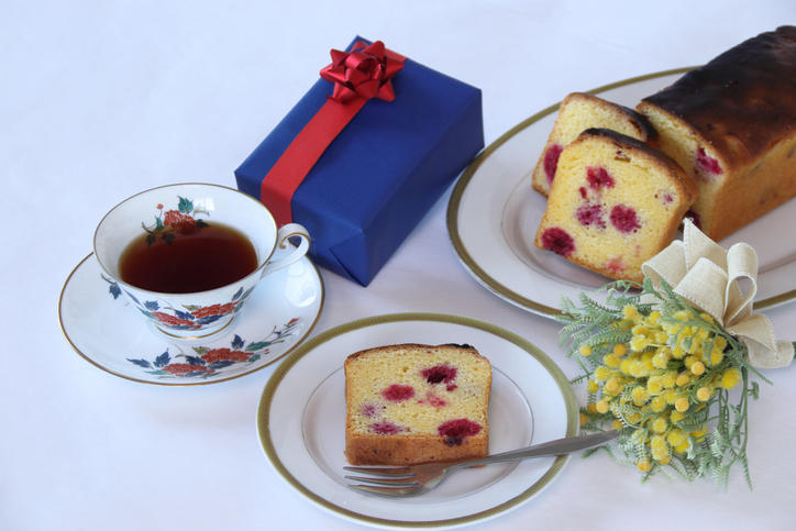 赤いリボンが付いた青のギフトボックスとパウンドケーキが並んでいる様子