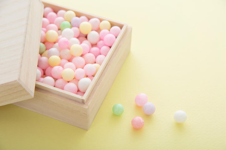 淡い黄色の背景に置かれた木箱入りのあられ菓子