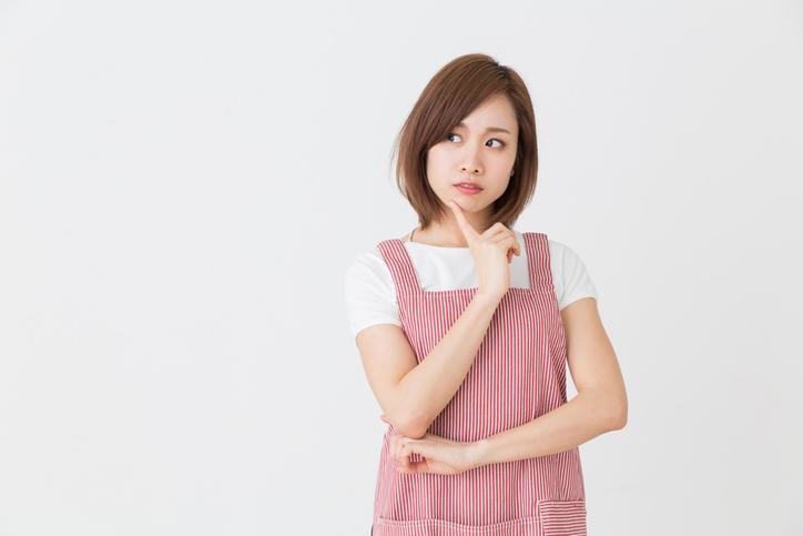 赤いストライプのエプロンをつけた女性が悩んでいる様子