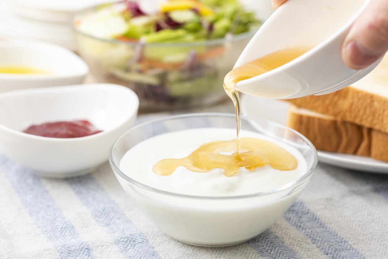 食卓でヨーグルトにはちみつを注ぐ様子
