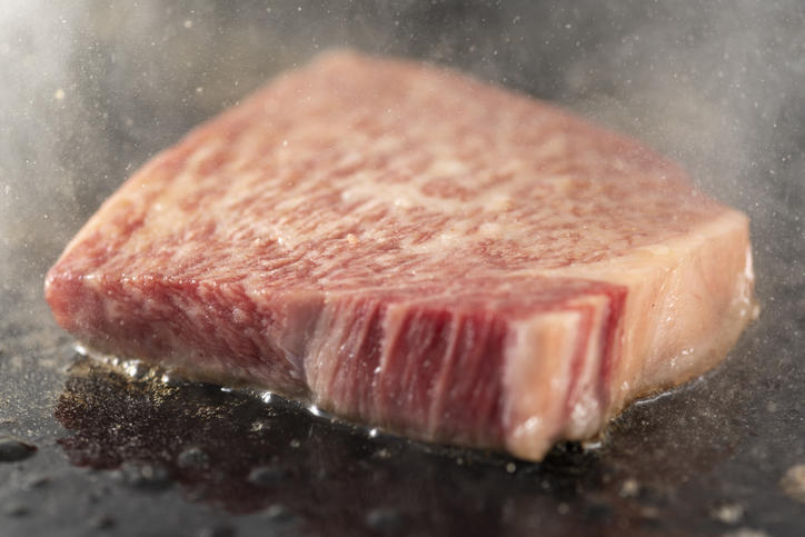 ステーキが鉄板で焼かれている