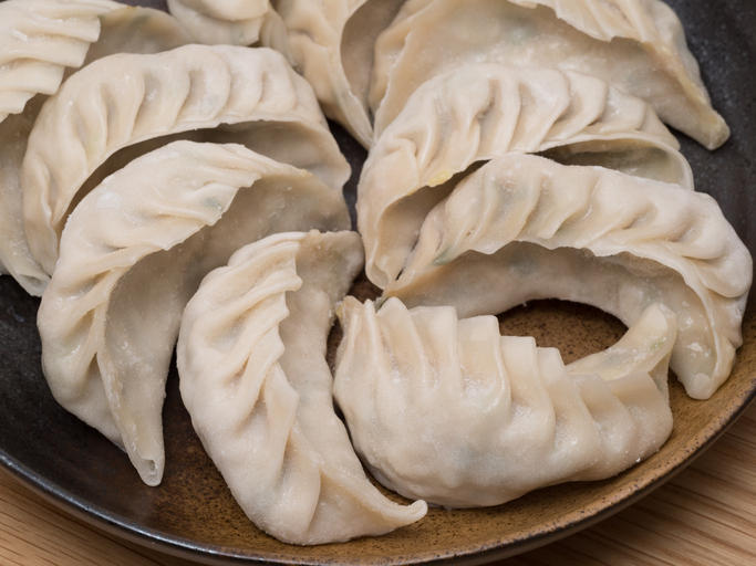 黒い皿の上に焼く前の餃子が並べられている
