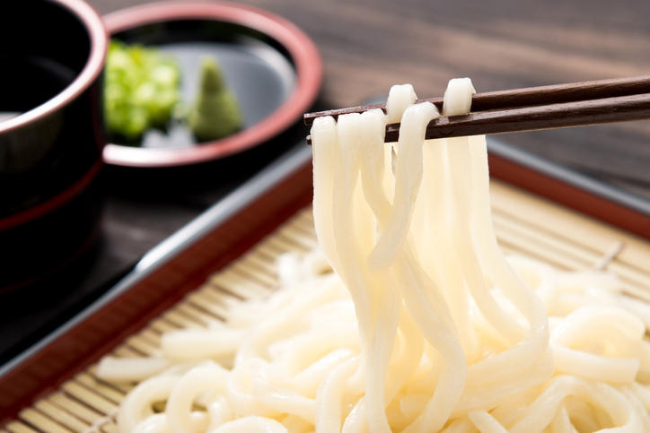 箸で持ち上げられているざるに盛られたうどん