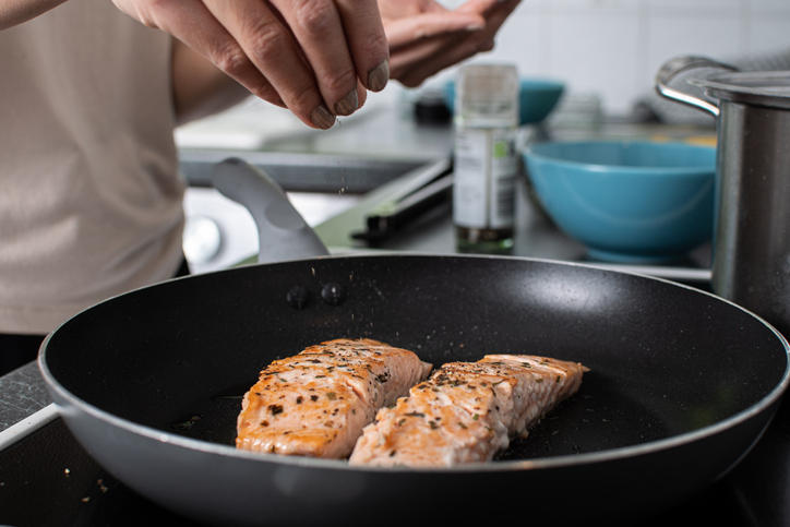 フライパンで魚を焼く人の手元