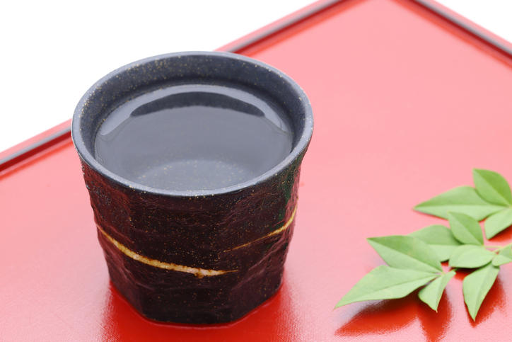 赤いトレイ上の黒い酒器に入れられたストレートの焼酎