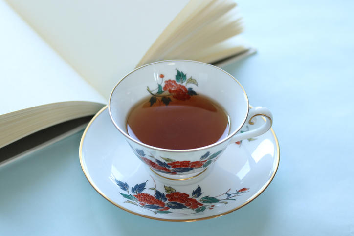 紅茶の入った白いティーカップと本が置かれている