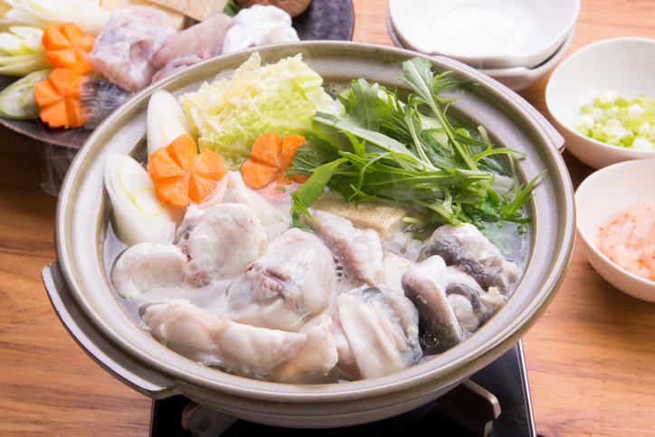 土鍋にふぐや水菜、にんじんなどの具材が入っている