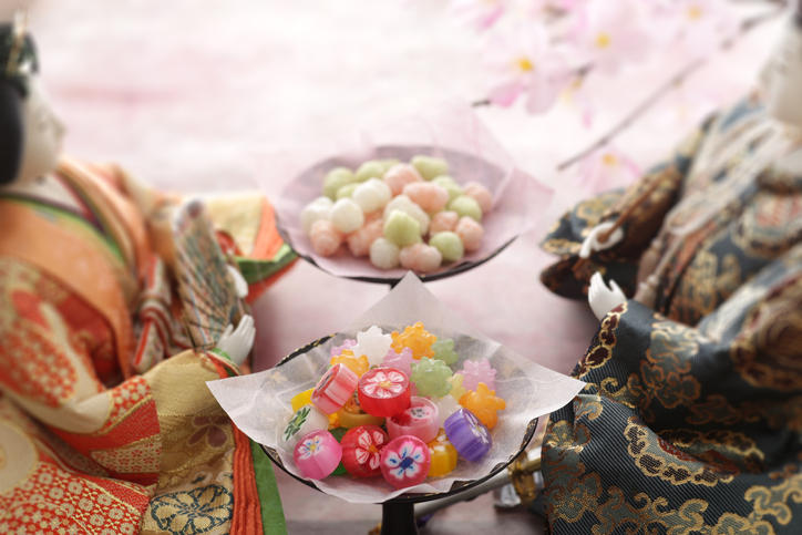 2体のひな人形の間に置かれたカラフルなお菓子
