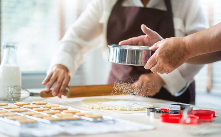 茶色のエプロンをつけた人がお菓子作りをしている
