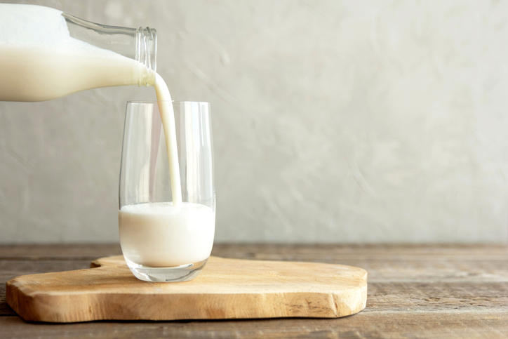 開封済みの牛乳が瓶からグラスに注がれている