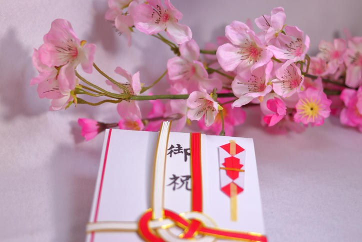 紅白蝶結びのご祝儀袋と桜の枝が置かれている様子