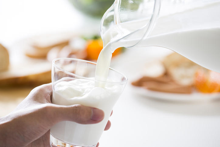 透明のデキャンタからグラスに牛乳が注がれている