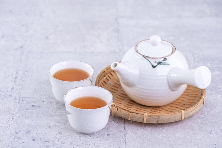 灰色のセメントの上に、番茶が入った白い湯呑2個と、平たいカゴの上に置かれた白い急須が並べられている