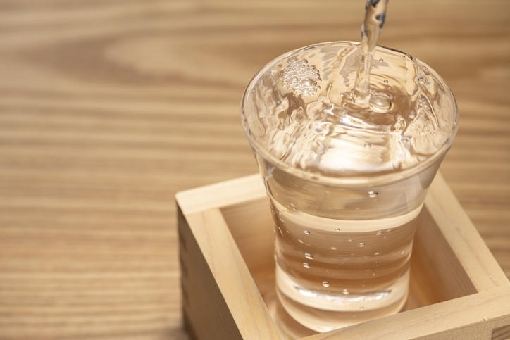 升に入れられたグラスに日本酒が注がれる様子