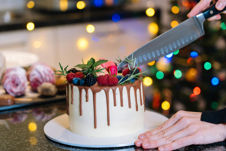チョコレートがかかったクリスマスケーキを包丁でカットしている