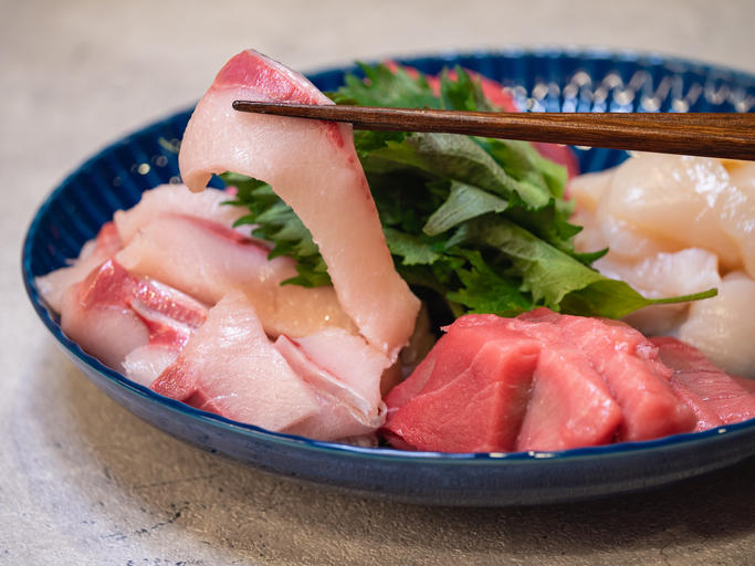 青い皿にいろいろな刺身が盛り付けられている