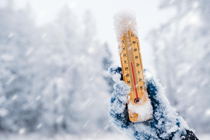 雪の中、手袋をはめた手で温度計をもっている様子