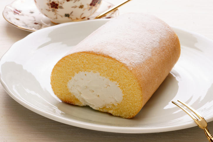 白い皿の上にカットしていないロールケーキ1本とデザートフォーク