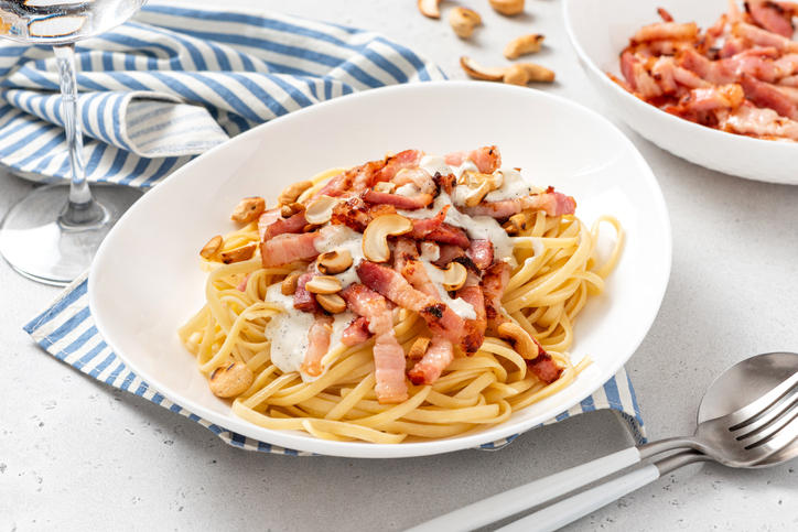 白い皿に盛り付けられたベーコンときのこのパスタ