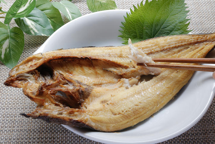 白い丸皿に盛り付けたホッケの身を箸でつまむ様子
