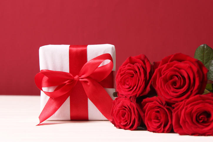 テーブルに置かれた赤いバラと赤いリボン付きのプレゼント