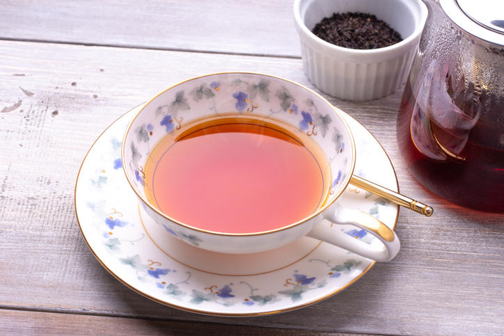 紅茶が注がれた青い花柄のティーカップとガラスのティーポットが置かれている
