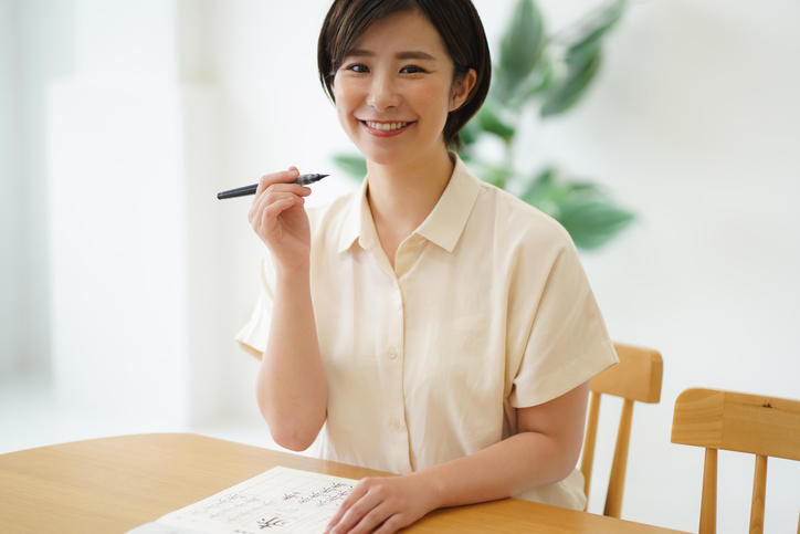 黒髪の女性がボールペンを手に持っている