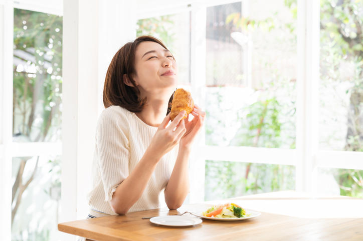女性がおいしそうに笑顔で食事をしている