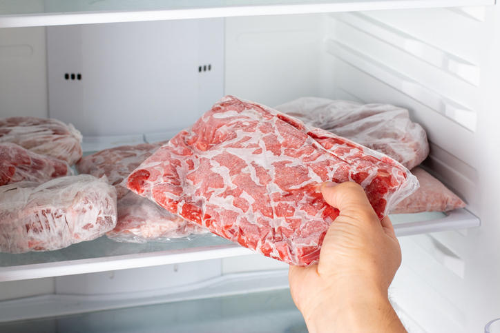 肉をラップで包み冷凍庫で保存しようとしている