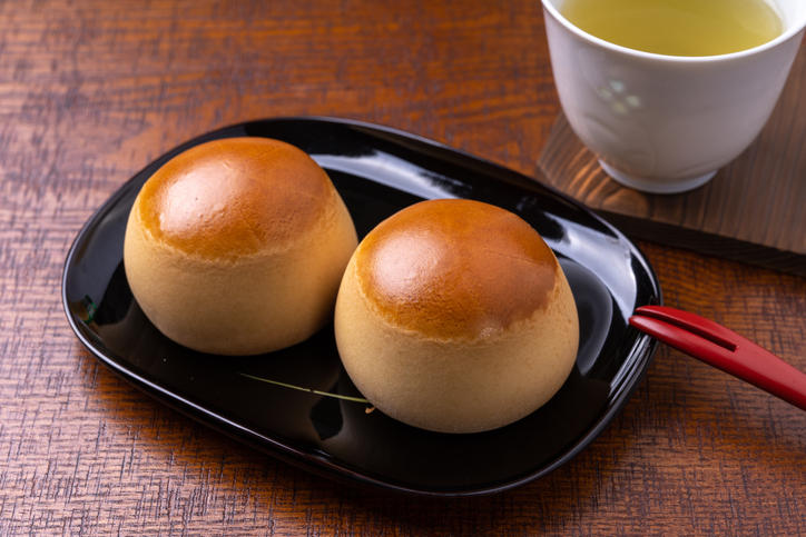 黒いお皿にのった栗饅頭とお茶