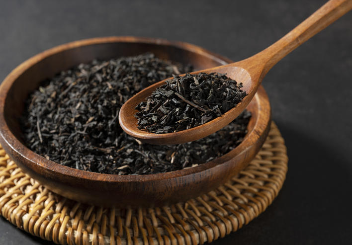 木製の器に紅茶の茶葉が入っており、それを木のスプーンですくっている