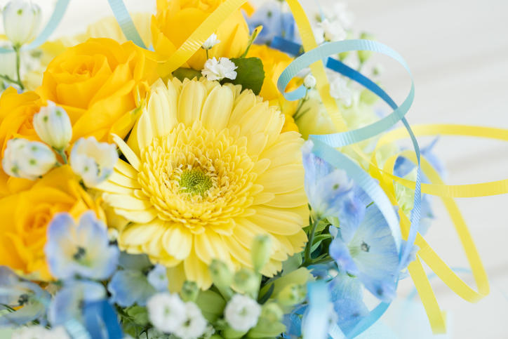 黄色いバラとガーベラ、白と青の小さい花の花束