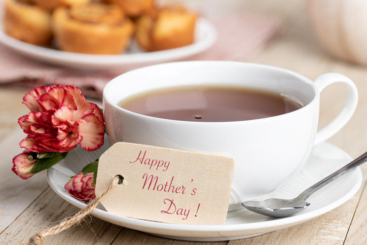 紅茶の入った白いカップアンドソーサーに赤いカーネーションと「happy mother's day」のタグが添えてある