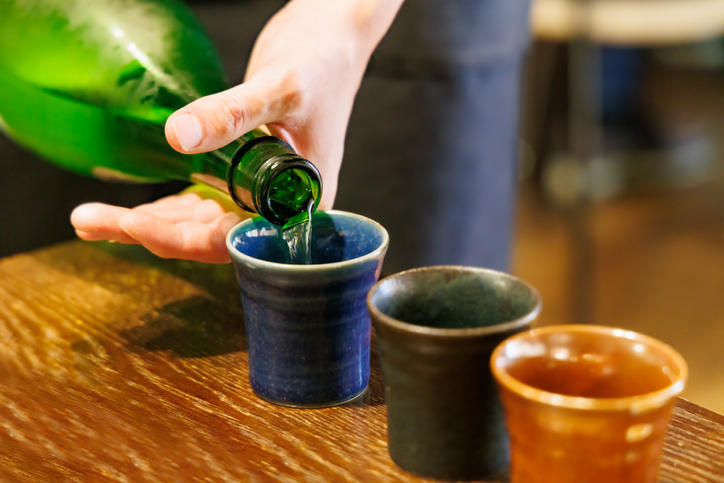色とりどりのおちょこに日本酒が注がれる様子