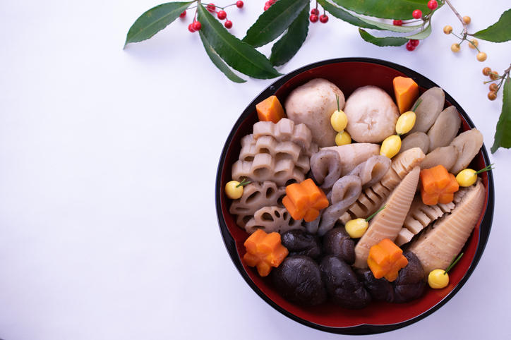 丸い赤と黒のお重に入った飾り切りが施された煮物