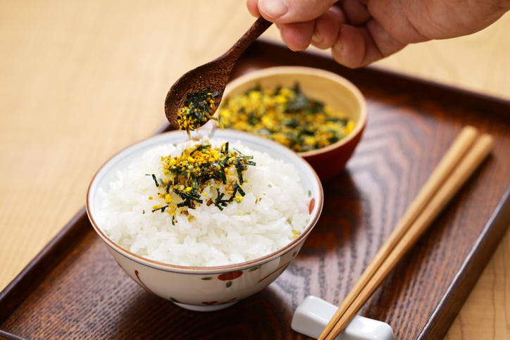 白いご飯に卵のふりかけをかける様子