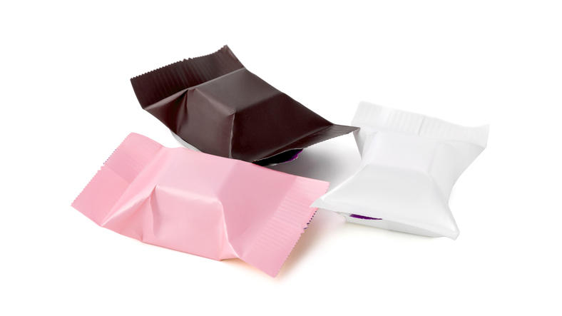 白いスペースに置かれた白、ピンク、茶色のお菓子の包み