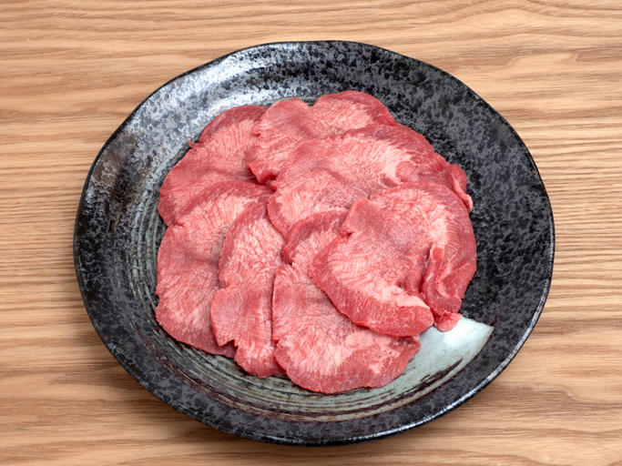 黒い皿のうえに牛タンが数枚並べられている
