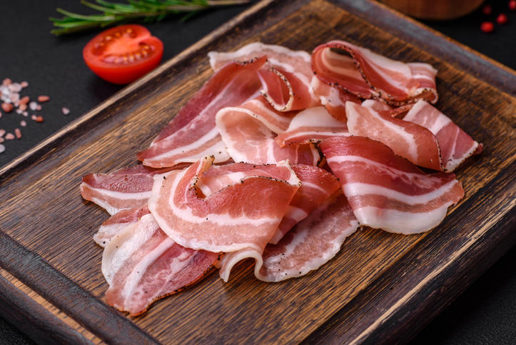 木の板の上に不規則に置かれた薄切りのパンチェッタ
