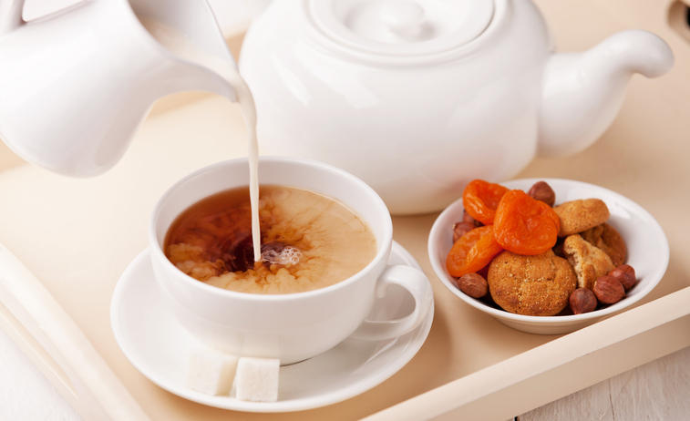 白いカップに入った紅茶にミルクを注ぐ様子