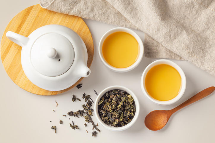 白いカップに注がれたお茶とティーポット、茶葉が入ったカップ