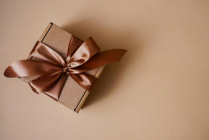 ベージュの背景に置かれたブラウンでまとめられたリボン付きギフトボックス