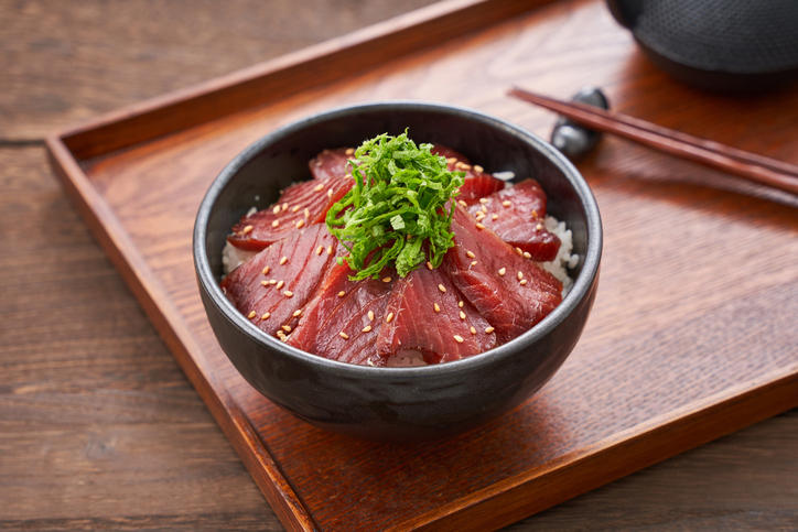 木製のトレーにのった黒い丼入りのマグロの漬け丼