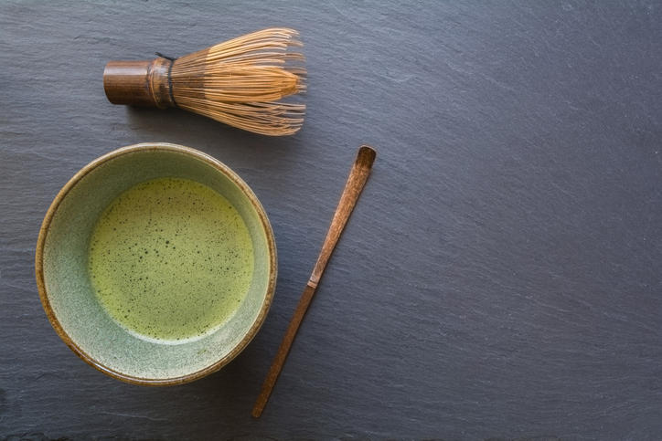石目調の黒背景に抹茶碗に入った抹茶と茶筅と茶杓