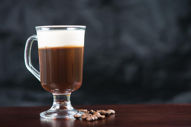 木製のテーブルに置かれたアイリッシュコーヒーのグラスとコーヒー豆